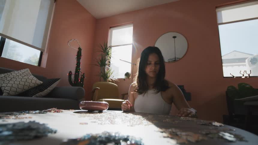 Woman sits in living room working on jigsaw puzzle