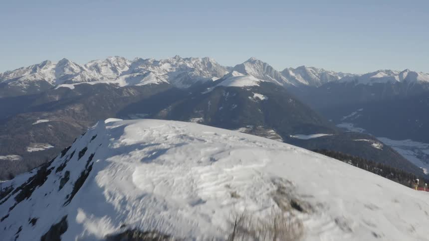 A snow covered mountain ridge and a mountain range in the distance with a valley below