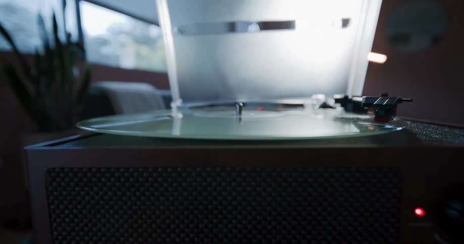 The reflection of the room shines on a vinyl record album as it spins on a turntable