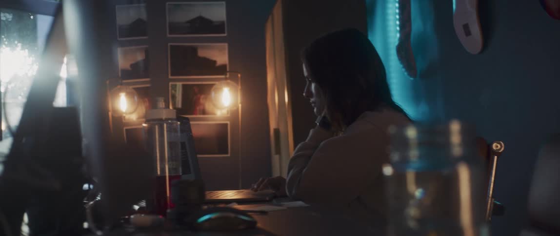 A woman sitting working on a laptop at home looking bored