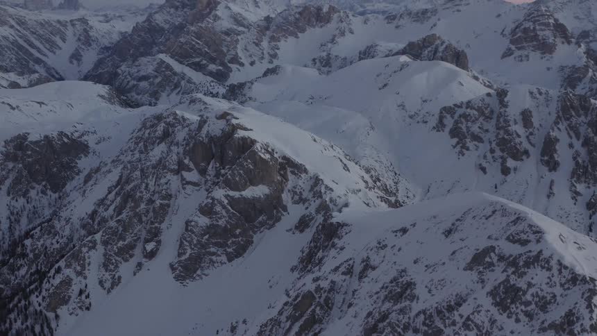 Aerial view of snow covered mountains at dusk is displayed