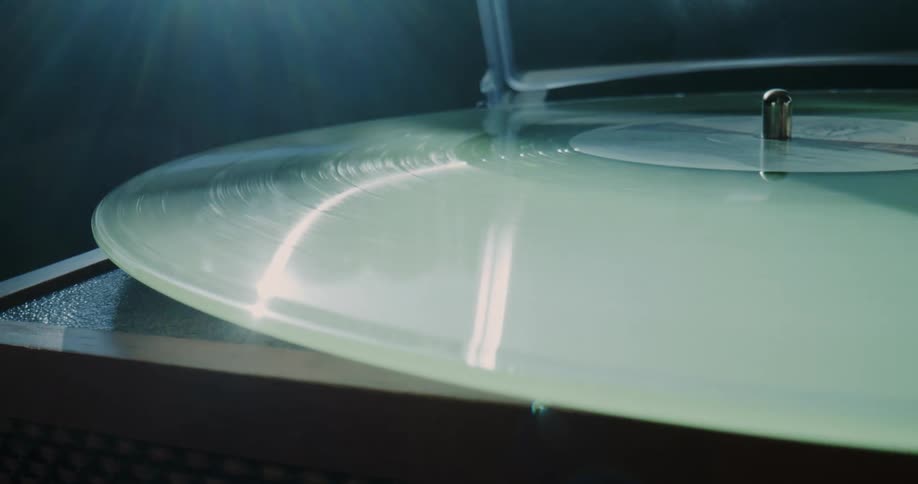 The sun shines on a vinyl record album as it spins on a turntable