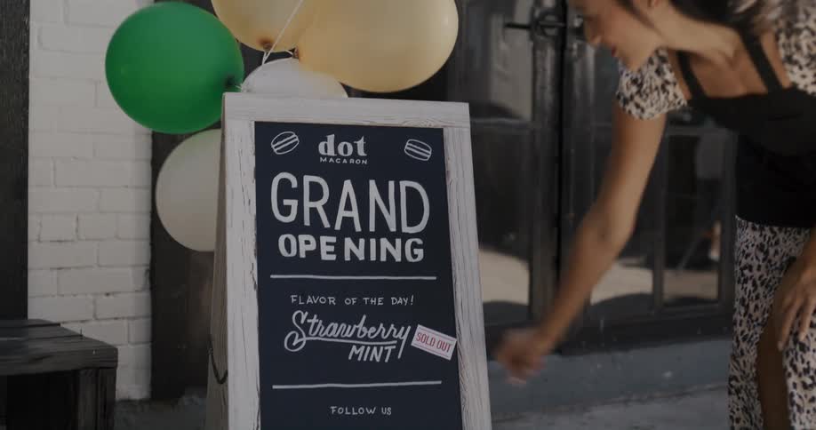 A woman places a sold out placard out a sign outside a business