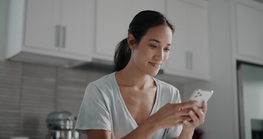 A woman smiling and looking pleased as she texts and scrolls on her phone