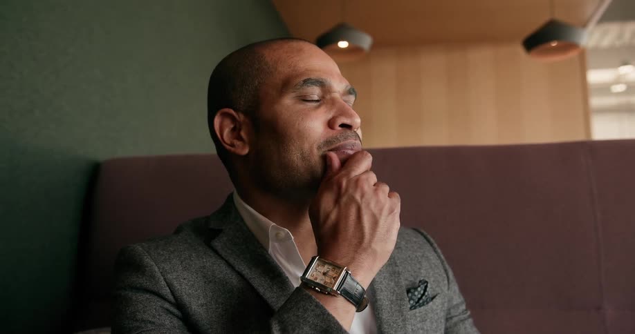 A man sits and rubs his chin thinking