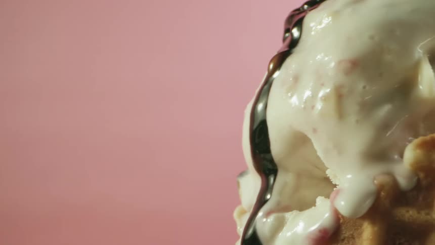 Chocolate syrup is poured on the ice cream cone