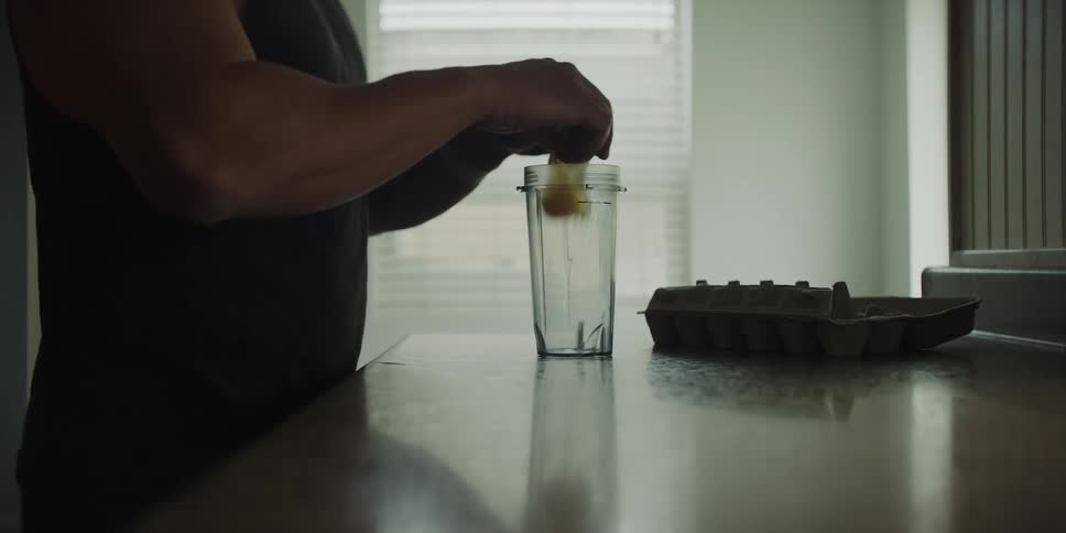 Man cracks several eggs into a glass