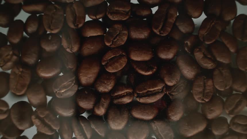 A person is pouring out coffee beans on a glass table