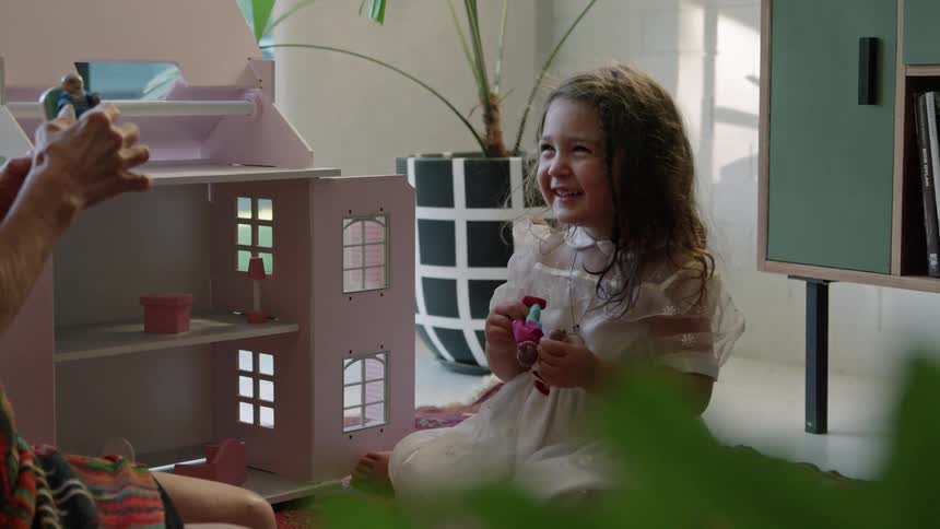 A child laughs as they plays with her dolls