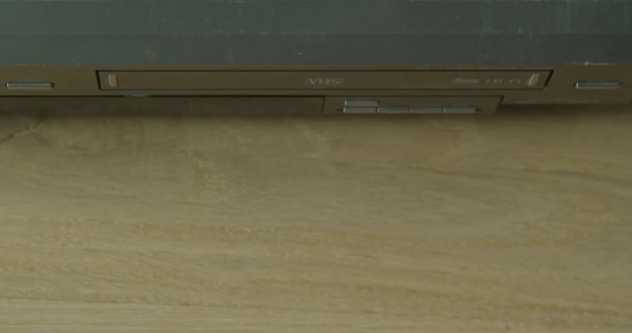 A person inserts a vhs tape in the player