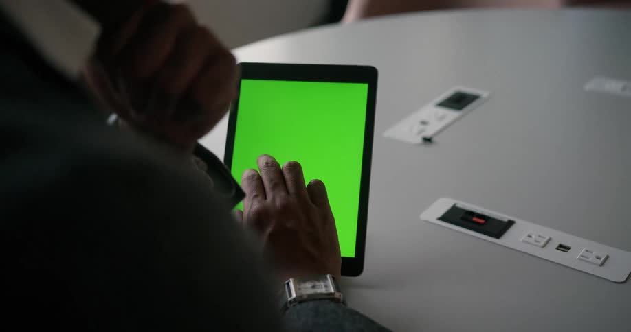 Man with blazer jacket want wristwatch sits at table using tablet