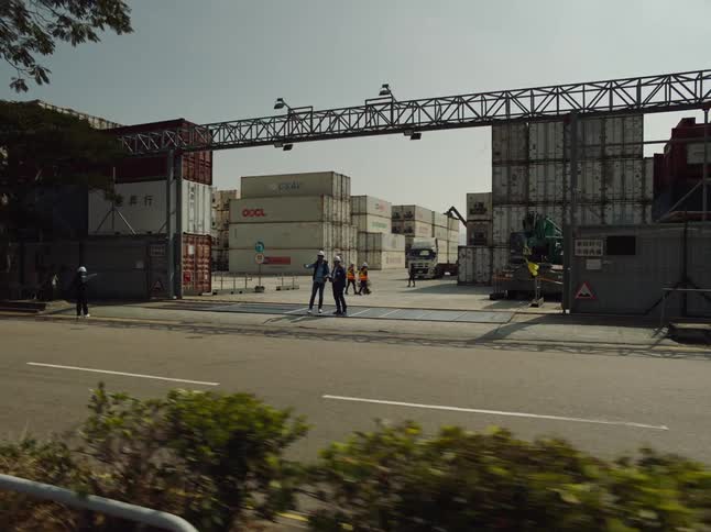 Men walk around a shipyard cargo area as they work
