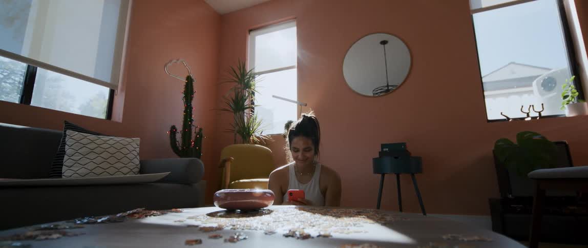 A woman uses her smartphone while sitting on the floor of her living room