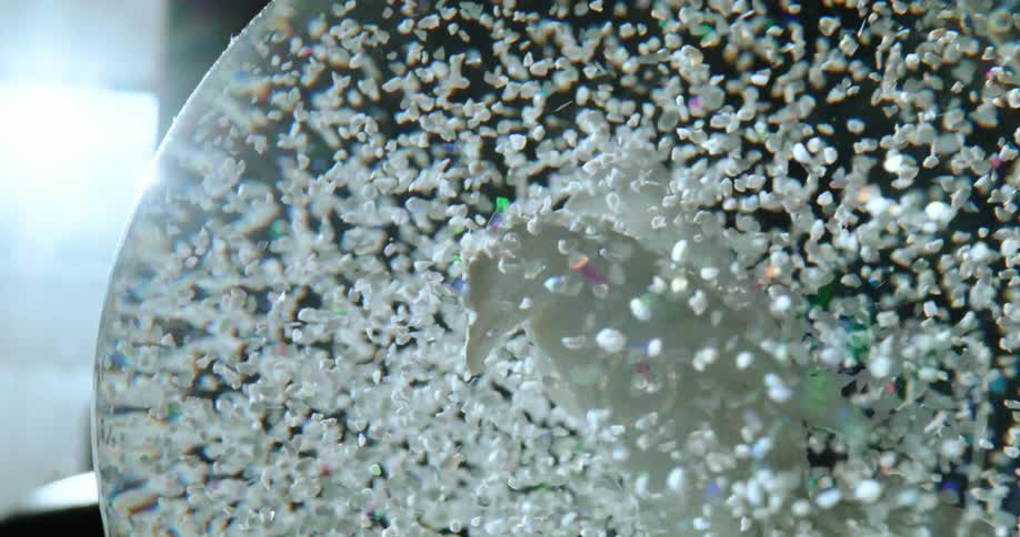 Simulated snow blows inside a shaken snow globe