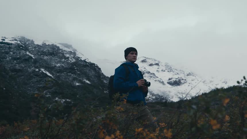 A photographer is up in the snowy mountains taking pictures