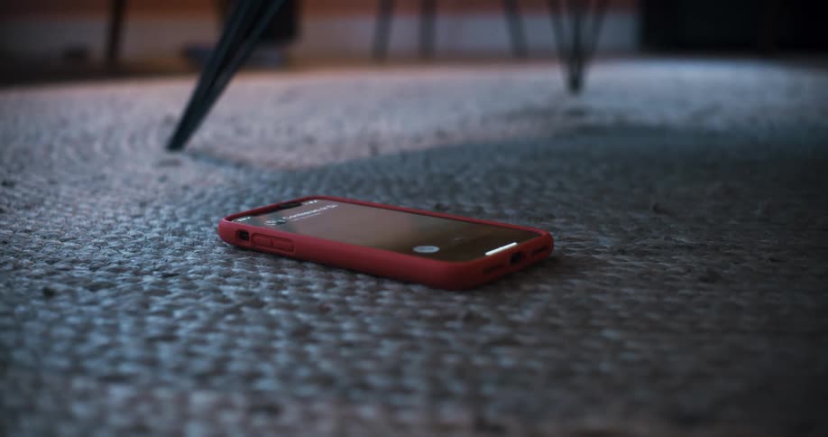 A cell phone lying on the floor lights up as it rings