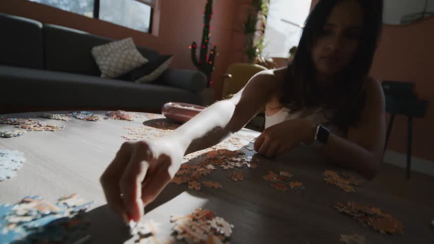 A woman working on a large jigsaw puzzle in her living room
