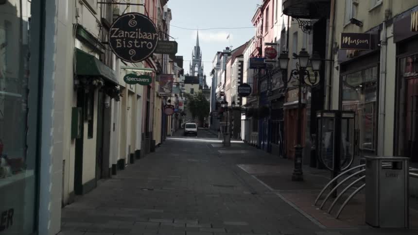 An alley sits empty with a vehicle in the distance
