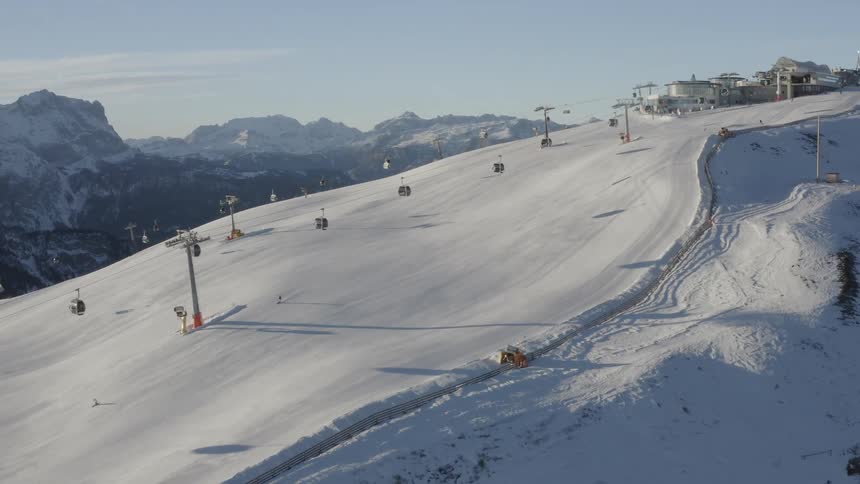 A ski lift carries people up and down a steep mountain