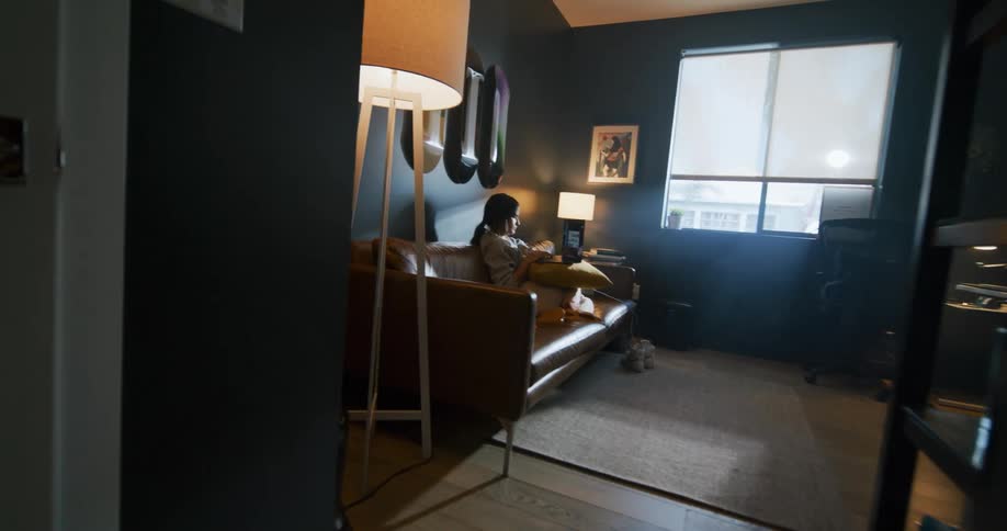 A female is sitting on a couch in her living room