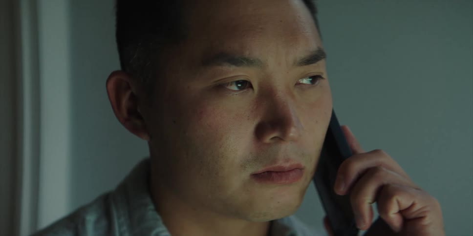 Man listens to phone call on mobile phone with a somber face
