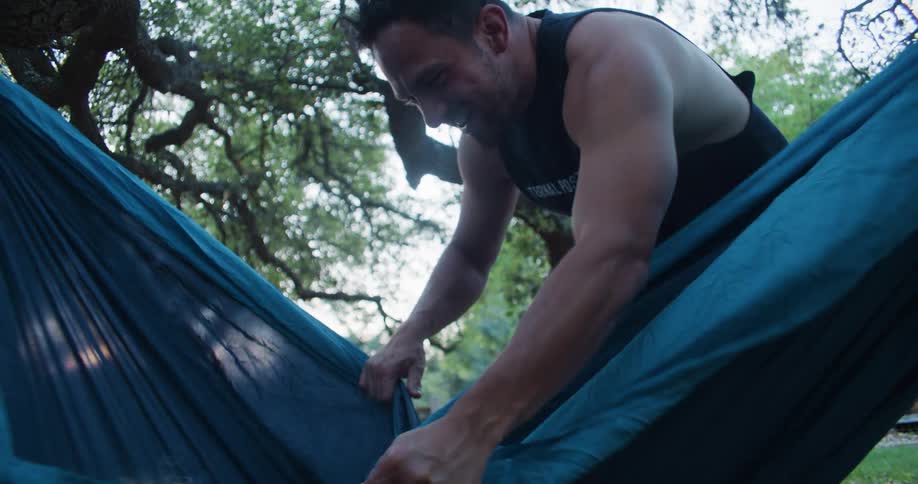 Father with black shirt plays with son lying in blue hammock