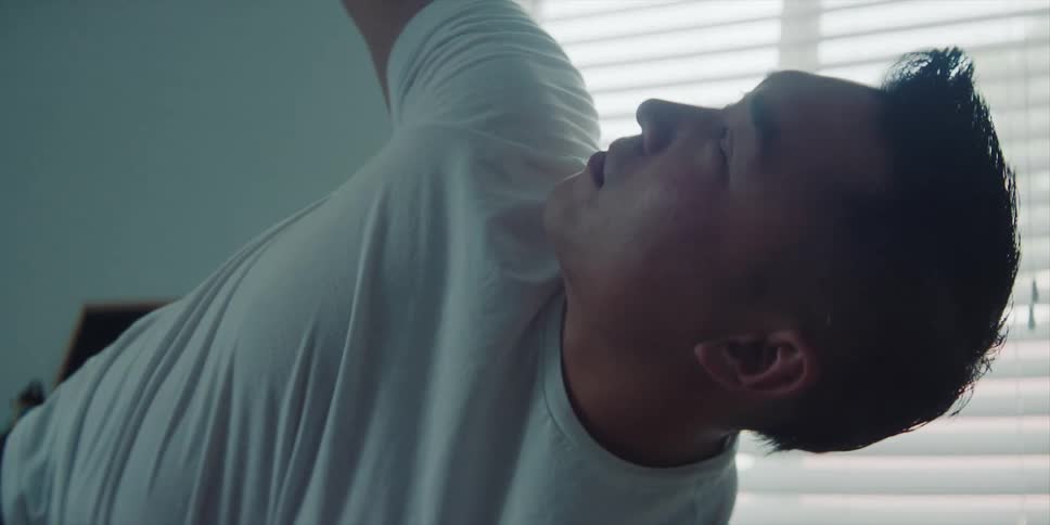 Man with white t shirt exercises next to windows