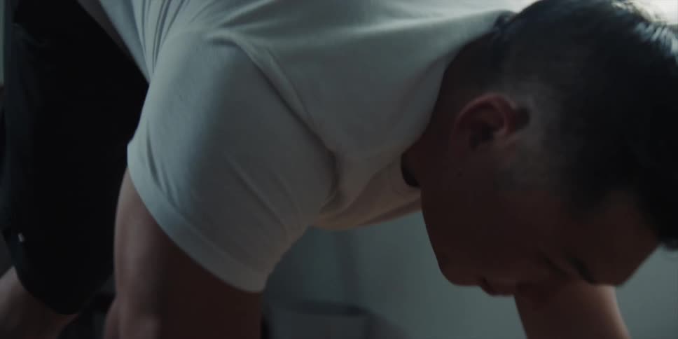 A man is doing stretches in his room during the daytime