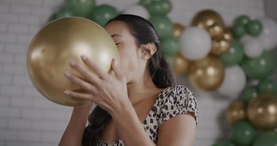 Woman smiles while inflating a balloon near a balloon display