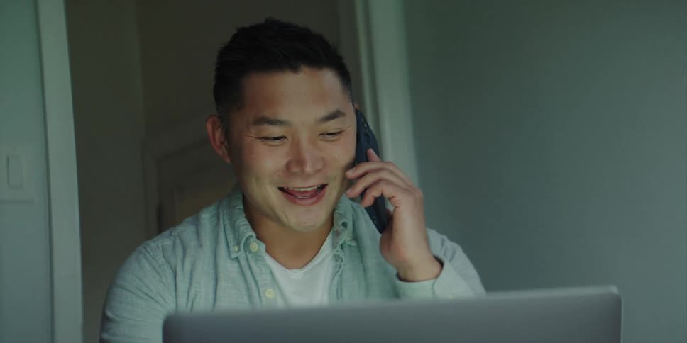 A man is talking on the phone and smiling