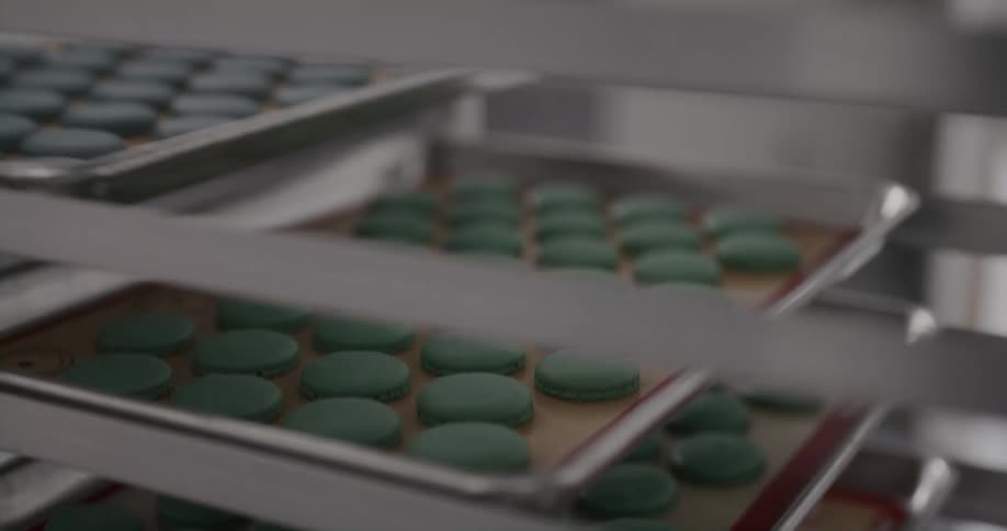 An employee slides trays of macaroons on to shelves