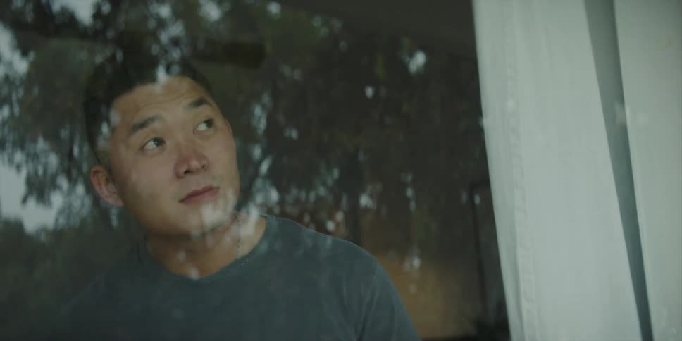 A man is in his house and looking out his window