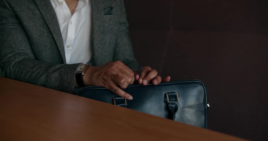 A man is putting his laptop in his bag and leaving his office
