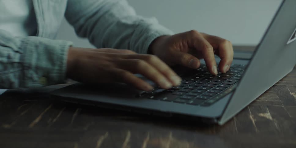 Professional asian man sitting at the desk in an office space typing on his laptop