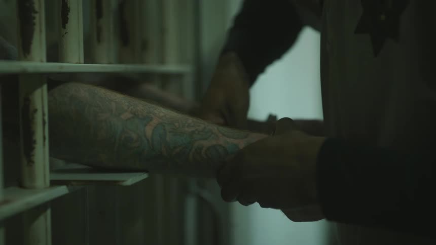 Prisoner puts hands through bars to allow handcuffs to be removed
