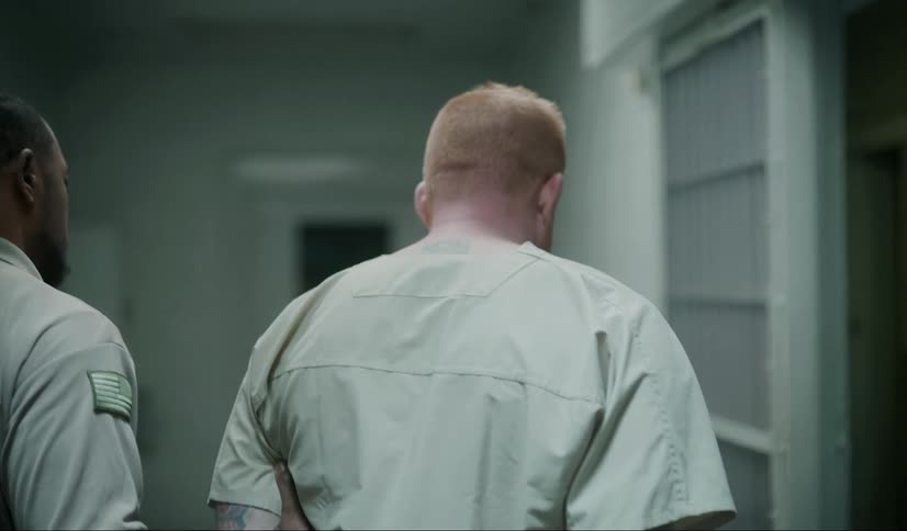 A prisoner is led down the jail corridor