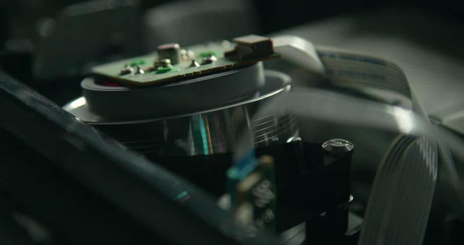 Close up of a small machine with a spinning top as a belt wraps around it