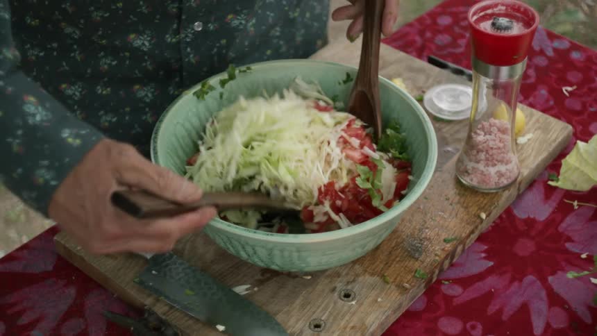 A man tosses a salad outside at home