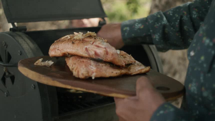 A man is grilling meat outdoors during the spring time