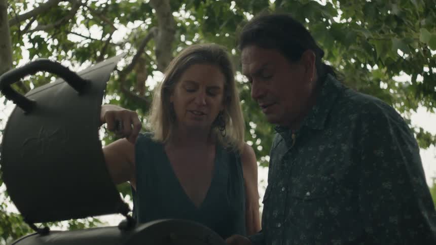A man and woman are talking and barbecuing outside