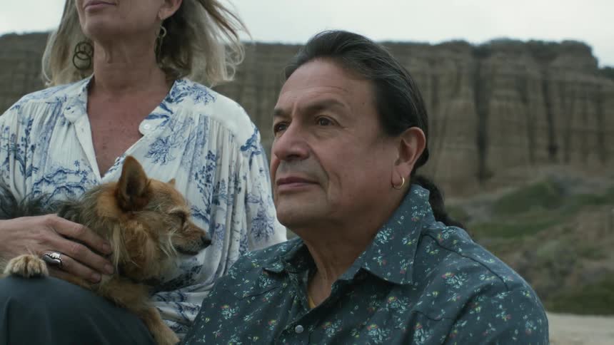 Man and woman are sitting outdoors with their dog