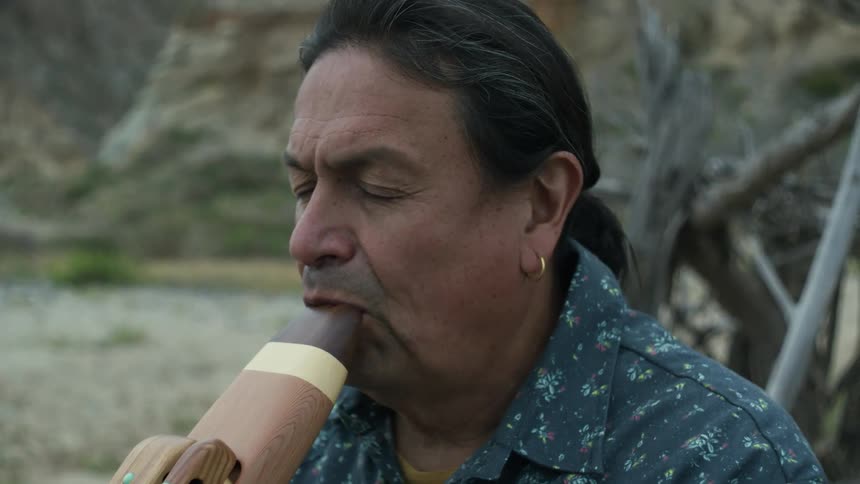 A man is playing an instrument while sitting outdoors