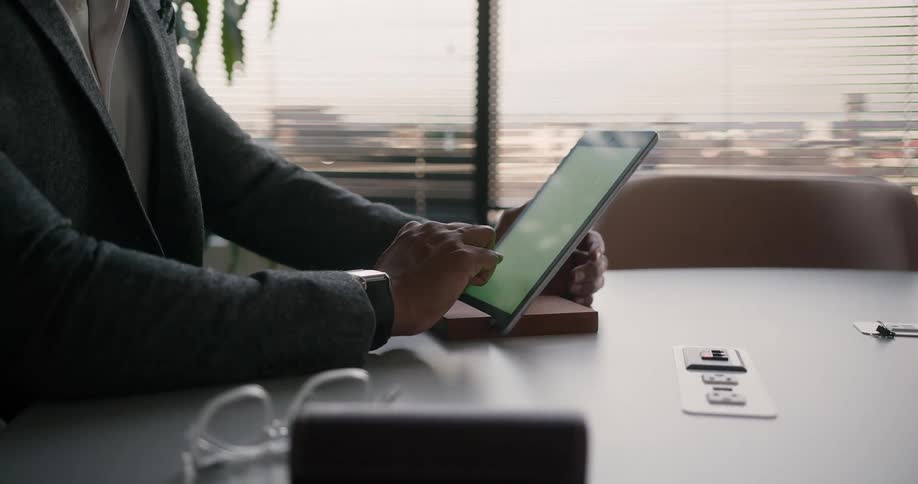 Black man sitting at his office desk alone using his tablet