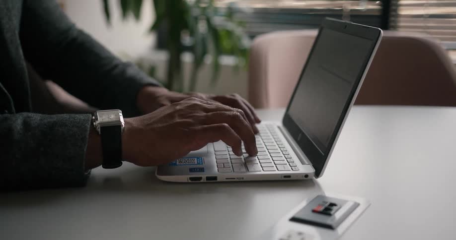 Professional man sitting at the desk in an office space typing on his laptop
