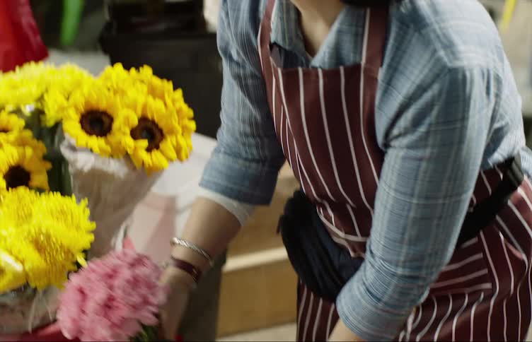 Female flower shop employee happily helping a woman choose a colorful bouquet of flowers