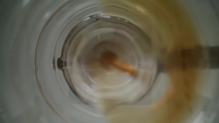 A liquid coffee beverage is brewing in a machine