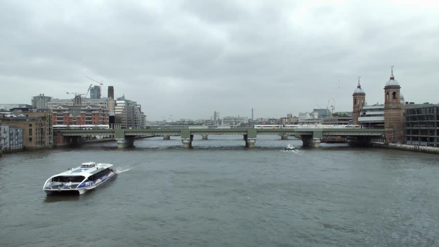 A large boat passes under a bridge on a cloudy day
