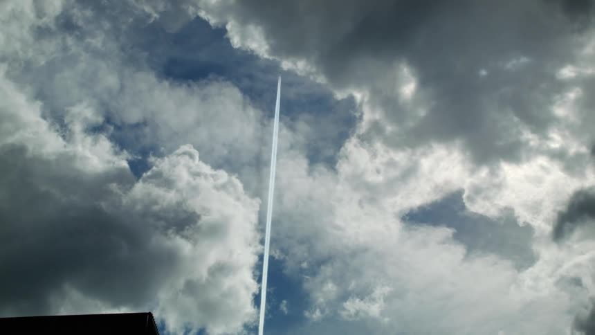 An aircraft rises high into the sky leaving a streak in the clouds