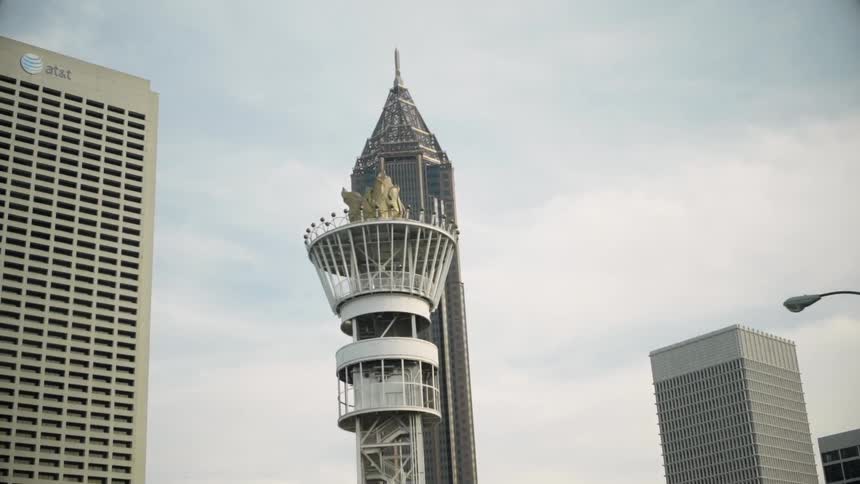 A tower that looks like a torch stands amongst tall buildings