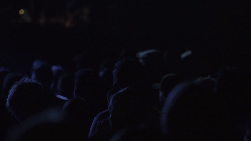 A crowd in a concert venue are bathed in blue lights
